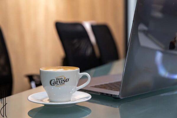 Porcelanowa filiżanka do espresso Don Caruso ze spodkiem obok laptopa