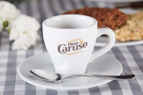 Porcelanowa filiżanka do espresso Don Caruso ze spodkiem obok talerza z jedzeniem